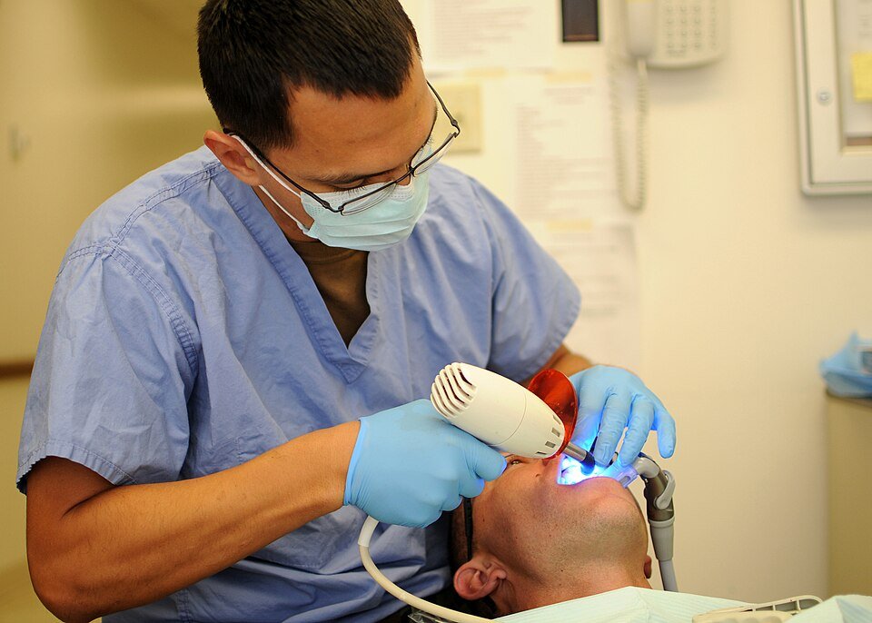 Dental bonding: a dentist hardens tooth-colored composite resin with a curing light